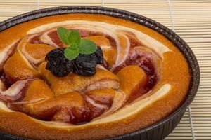 Plum cake in a bowl on wooden background photo