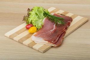 Prosciutto on wooden board and wooden background photo