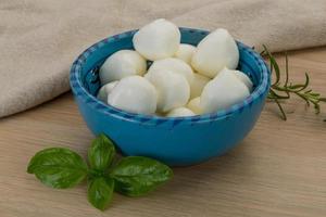 Mozzarella cheese in a bowl on wooden background photo