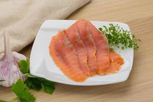 Sliced salmon on the plate and wooden background photo