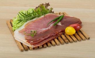 Prosciutto on wooden board and wooden background photo