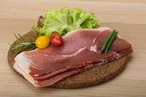Prosciutto on wooden board and wooden background photo