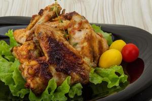 alitas de pollo en el plato y fondo de madera foto