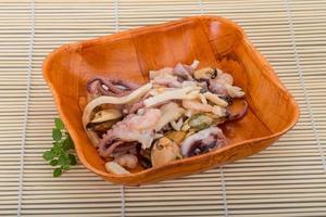 Seafood cocktail in a bowl on wooden background photo