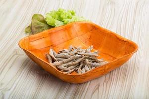 Dries anchovy in a bowl on wooden background photo