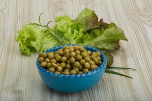 Marinated peas in a bowl on wooden background photo