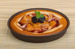 Plum cake in a bowl on wooden background photo