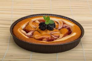 Plum cake in a bowl on wooden background photo