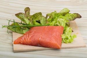 Salmon fillet on wooden board and wooden background photo