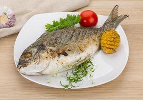 Grilled dorado on the plate and wooden background photo