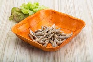 Dries anchovy in a bowl on wooden background photo