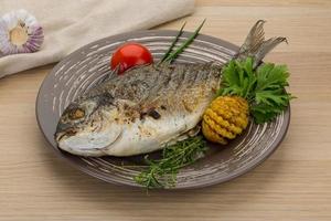 Grilled dorado on the plate and wooden background photo