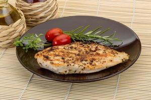 Grilled chichen breast on the plate and wooden background photo