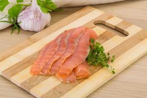 Sliced salmon on wooden board and wooden background photo