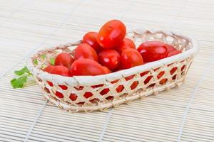 Cherry tomato in a basket on wooden background photo