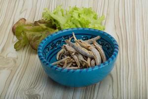 Dries anchovy in a bowl on wooden background photo