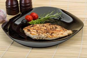 Grilled chichen breast on the plate and wooden background photo