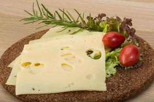 Maasdam cheese on wooden board and wooden background photo