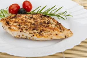 Grilled chichen breast on the plate and wooden background photo