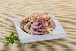 Seafood cocktail in a bowl on wooden background photo