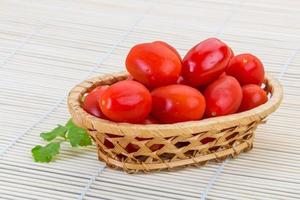 Cherry tomato in a basket on wooden background photo