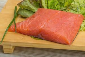 Salmon fillet on wooden board and wooden background photo