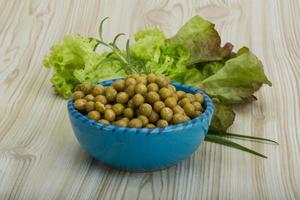 Marinated peas in a bowl on wooden background photo