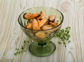 Mussels in a bowl on wooden background photo