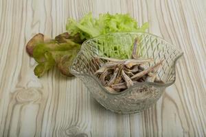 Dries anchovy in a bowl on wooden background photo