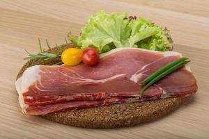 Prosciutto on wooden board and wooden background photo