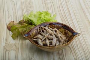 Dries anchovy in a bowl on wooden background photo