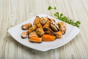 Mussels on the plate and wooden background photo