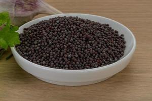 Black mustard seeds on wooden background photo