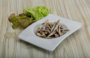 Dries anchovy in a bowl on wooden background photo