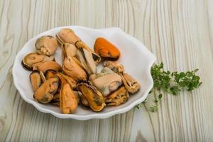 Mussels in a bowl on wooden background photo