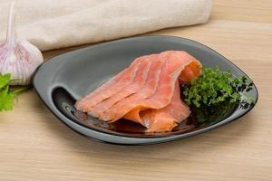 Sliced salmon on the plate and wooden background photo