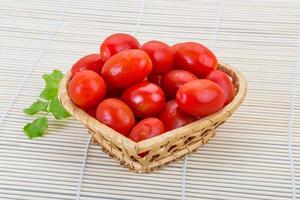 Cherry tomato in a basket on wooden background photo