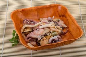 Seafood cocktail in a bowl on wooden background photo