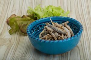 Dries anchovy in a bowl on wooden background photo