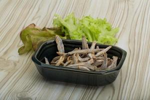 Dries anchovy in a bowl on wooden background photo