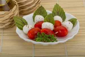 ensalada caprese en el plato y fondo de madera foto