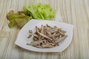 seca la anchoa en el plato y el fondo de madera foto