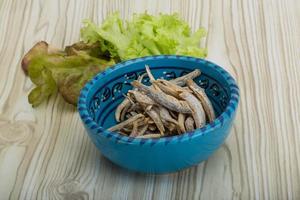 Dries anchovy in a bowl on wooden background photo
