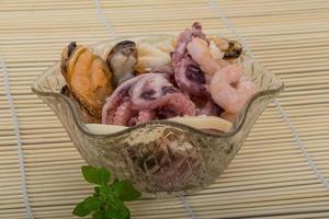 Seafood cocktail in a bowl on wooden background photo