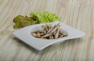 Dries anchovy in a bowl on wooden background photo