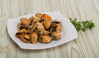 Mussels on the plate and wooden background photo