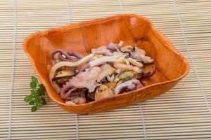 Seafood cocktail in a bowl on wooden background photo