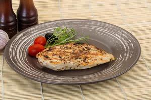 Grilled chichen breast on the plate and wooden background photo