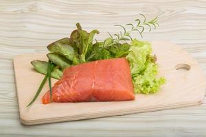 Salmon fillet on wooden board and wooden background photo