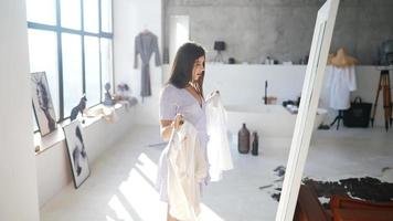 jeune femme en robe d'été vérifie les vêtements dans le miroir video